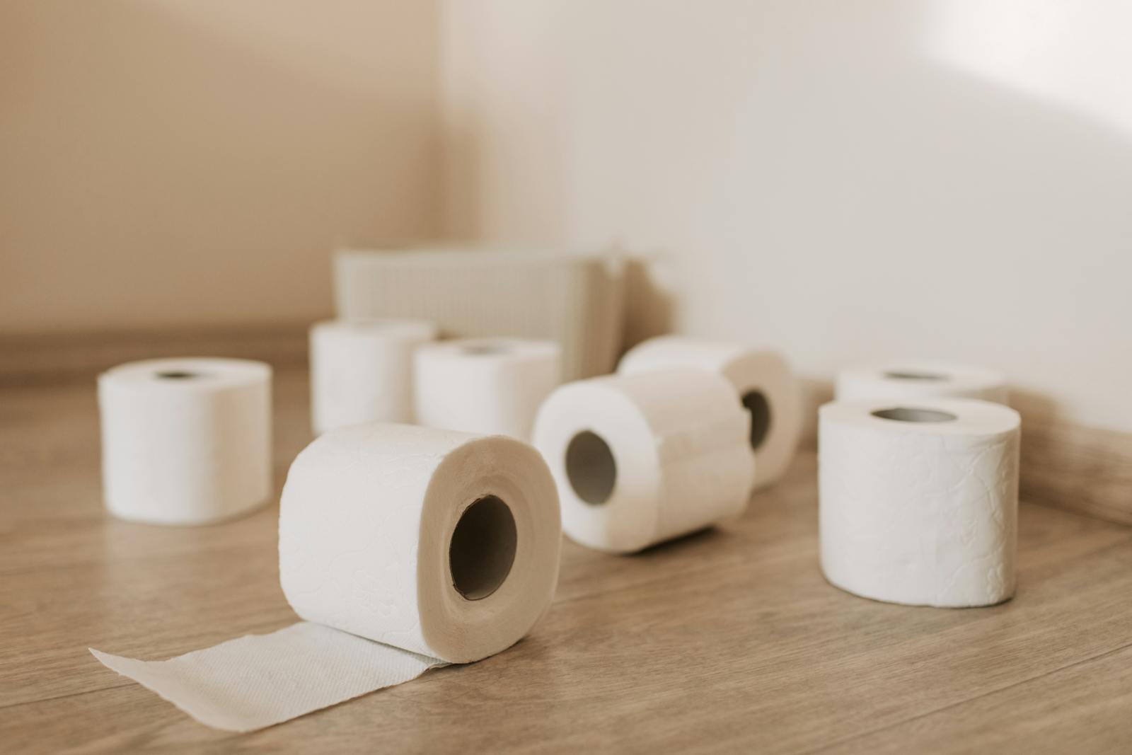 A neat arrangement of toilet paper rolls on a wooden floor, indoor setting.