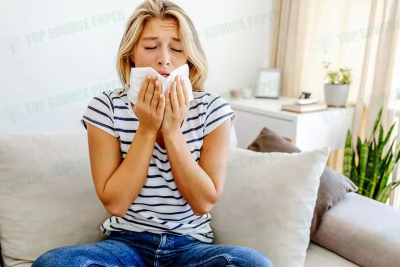 Attractive young woman feeling ill, blowing her nose with a tissue.
