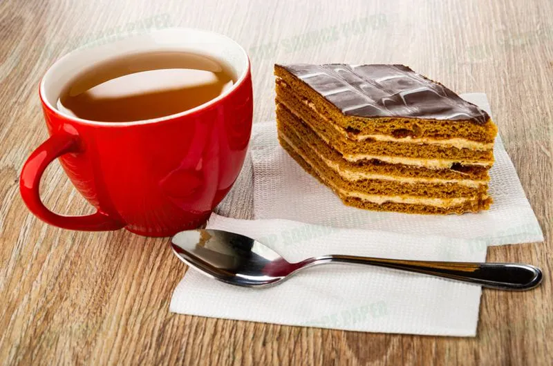 A cup of tea and a slice of chocolate cake with a teaspoon