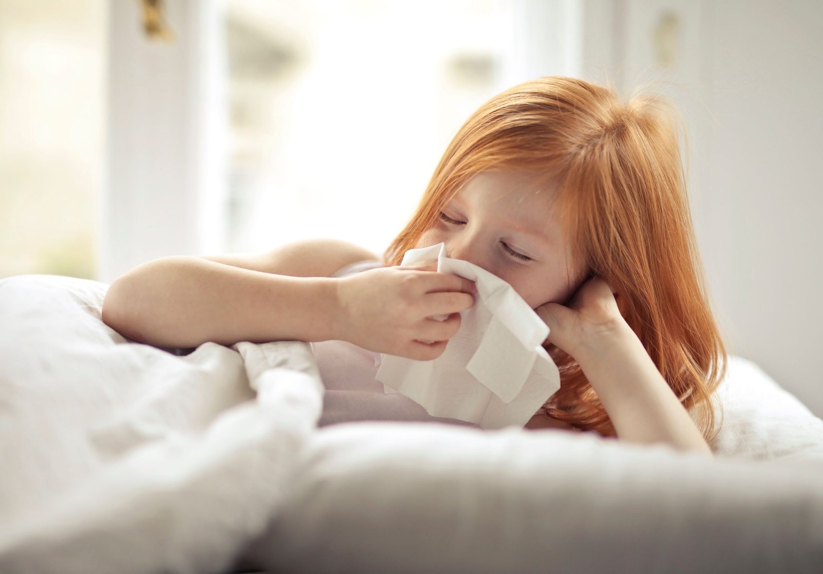 Child blowing her nose with a soft facial tissue at home