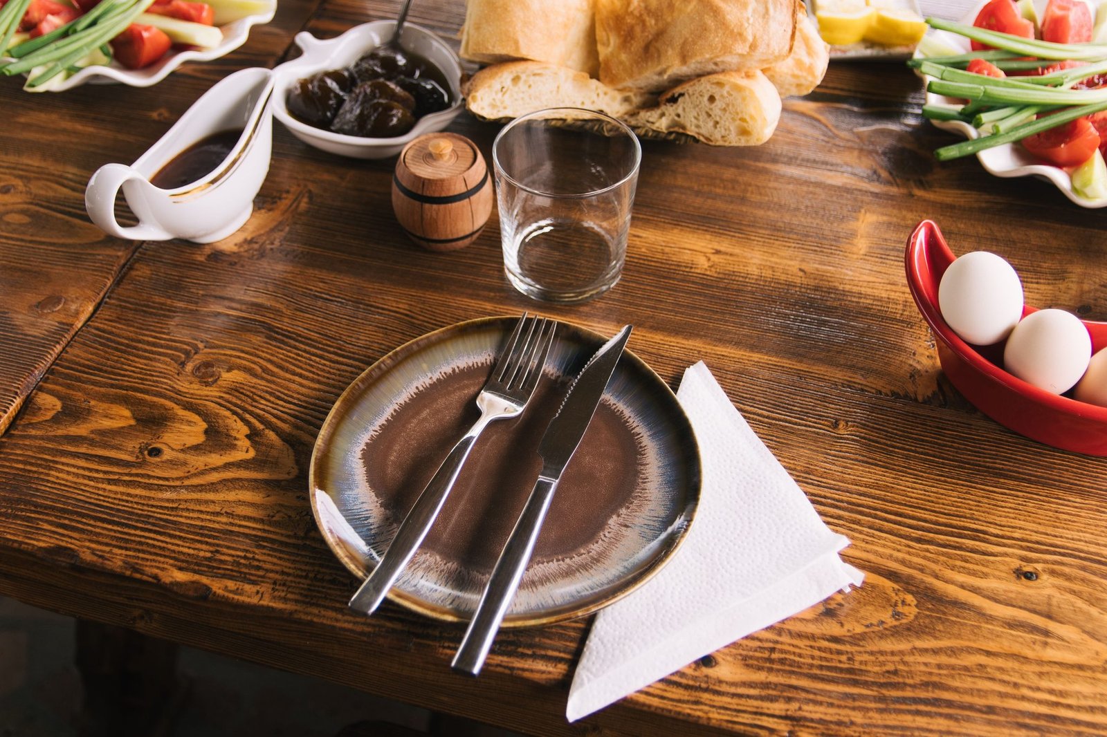 Paper dinner napkin set beside a plate and cutlery on a rustic wooden table