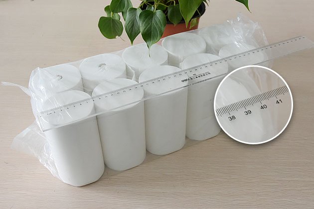 Shrink-wrapped pack of toilet paper rolls measured with a ruler for roll count and length