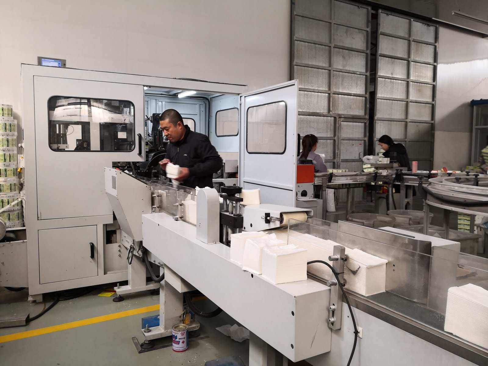 Operator lifting folded facial tissue stacks from the folding line outfeed